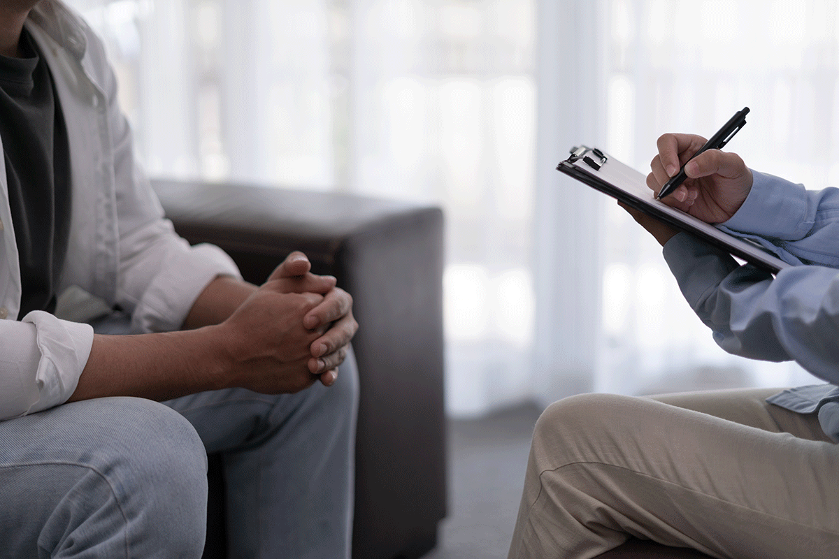 a patient sits on a couch while her therapist writes down on notepad about the most effective treatment for bipolar disorder