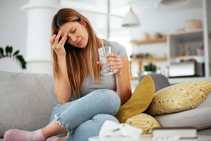 woman sitting on couch suffering from symptoms related to home detoxing